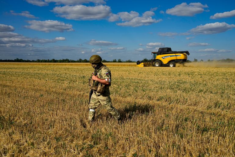 A Russian soldier guards an area during foreign journalists watch and film as farmers of the Voznesenka-Agro farm harvest with their combine in a wheat field not far from Melitopol, south Ukraine, Thursday, July 14, 2022. About 300,000 tonnes of harvest have been collected in Melitopol district of Zaporizhzhia region. Russia took control of part of the Zaporizhzhia region quickly after the launch of the military operation in Ukraine. This photo was taken during a trip organized by the Russian Ministry of Defense. (AP Photo)