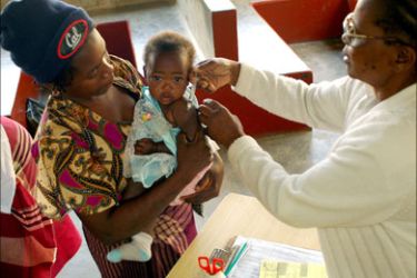 r - A health worker vaccinates a child from Mozambique against measles at a provincial hospital in Xai Xai, 200 km (125 miles) north of the capital Maputo, August 11, 2005
