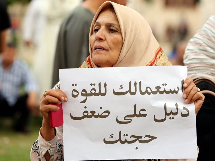 GUE330 - Tripoli, -, LIBYA : A Libyan woman holds a placard during a demonstration against the armed militias surrounding the Ministry of Foreign Affairs and the Ministry of Justice at Algeria Square on May 3, 2013 in Tripoli, Libya. Clashes erupted in the Libyan capital on May 3 between crowds demonstrating against militias in the city and supporters of a law to exclude Kadhafi-era officials from top government jobs, an AFP journalist said. Several hundred people gathered in Tripoli's central Algeria Square to protest against militias that have been laying siege to the justice and foreign ministries to call for the sacking of officials from the ousted regime of Moamer Kadhafi. AFP PHOTO/MAHMUD TURKIA