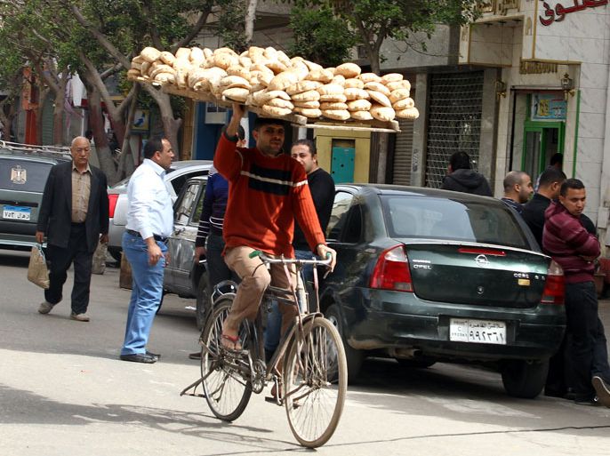 epa03615243 An Egyptian man carries a wood rack full of bread on his head on a bike, to distributed it to customers in Cairo, Egypt, 08 March 2013. Media reports state on 08 March, President for Foreign Relations Khaled Qazaz on a visit in Washington DC, said the IMF loan to Egypt will soon be announced which the government hopes it could alleviate the ailing economy. EPA/KHALED ELFIQI