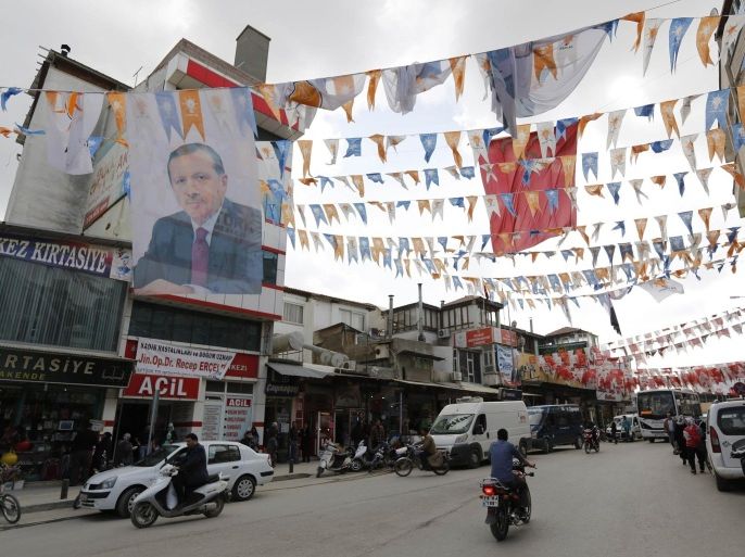 Flags of different political parties and a poster of Turkey's Prime Minister Tayyip Erdogan hang in the main square of the border city of Kilis on the Turkish-Syrian border March 18, 2014. Residents on the Turkey-Syria border area say Prime Minister Erdogan's ruling AK Party has mishandled the Syria crisis and exacerbated its impact on their province, and they plan to punish the party in Turkey's municipal elections on March 30. Erdogan has strongly backed opponents of President Bashar al-Assad since Syria's civil war erupted in 2011. Turkey opened its border to let in some 900,000 Syrian refugees, built camps to house them and gave free passage into Syria for the armed fighters, now dominated by hardline Islamists, battling Assad. Picture taken March 18, 2014. REUTERS/Murad Sezer (TURKEY - Tags: POLITICS ELECTIONS)
