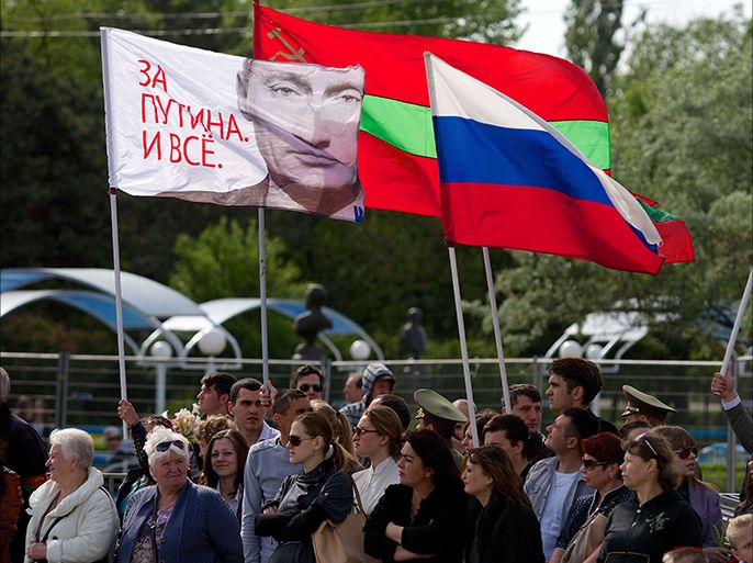 People carry a Russian flag (C) and a flag with a portait of Russia's President Vladimir Putin reading "We are for Putin!" in Tiraspol, the main city of Transdniestr separatist republic of Moldova, on May 9, 2014, during Victory Day celebrations. Transnistria, a small strip of land of 500,000 inhabitants in eastern Moldova, has won the support of Russia, a short war of independence after the collapse of the USSR in 1991. It is not recognized by the international community. AFP PHOTO/ VADIM DENISOV
