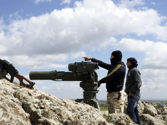 A rebel fighter of the Southern Front of the Free Syrian Army gestures while standing with his fellow fighter near their weapons at the front line in the north-west countryside of Deraa March 3, 2015. Syrian government forces have taken control of villages in southern Syria, state media said on Saturday, part of a campaign they started this month against insurgents posing one of the biggest remaining threats to Damascus. Picture taken March 3, 2015. REUTERS/Stringer (SYRIA - Tags: POLITICS CIVIL UNREST CONFLICT MILITARY)