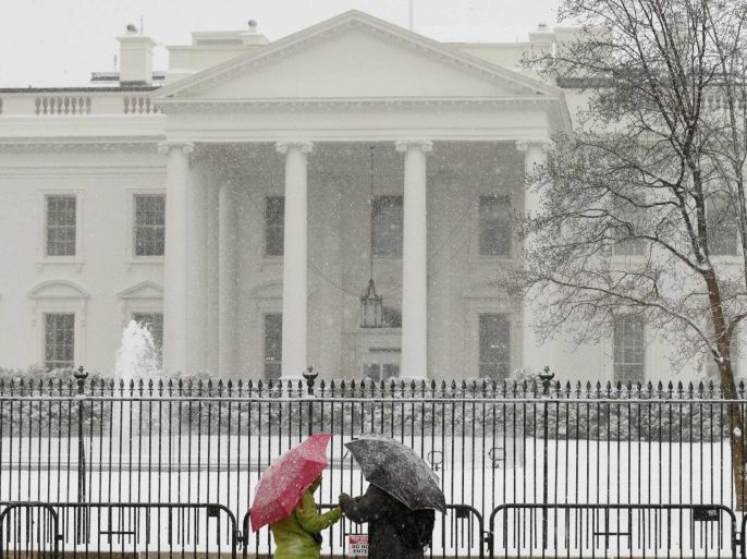 A couple stands in front of the White House as snow falls in Washington March 5, 2015. Federal offices were closed today due to the predicted snowfall of up to 7 inches in the nation's capital. A large winter storm reaching from Texas to southern New England had dumped over a foot (30 cm) of snow on parts of the eastern United States by early Thursday morning. REUTERS/Kevin Lamarque (UNITED STATES - Tags: ENVIRONMENT SOCIETY)