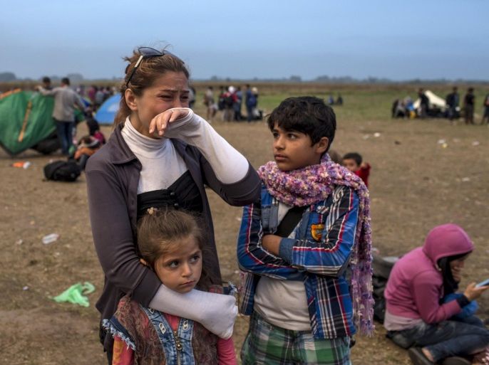 A migrant from Syria cries as she stands with her children on a field after crossing into Hungary from the border with Serbia near the village of Roszke, September 5, 2015. Austria and Germany threw open their borders to thousands of exhausted migrants on Saturday, bussed to the Hungarian border by a right-wing government that had tried to stop them but was overwhelmed by the sheer numbers reaching Europe's frontiers. Left to walk the last yards into Austria, rain-soaked migrants, many of them refugees from Syria's civil war, were whisked by train and shuttle bus to Vienna, where many said they were resolved to continue on to Germany. REUTERS/Marko Djurica