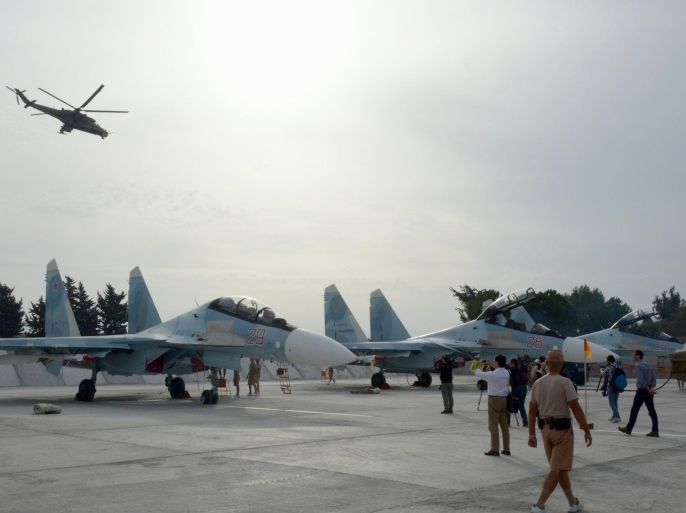 Journalists film Su-30 jets parked at Hemeimeem airbase, Syria, on Thursday, Oct. 22, 2015, as Mi 24 helicopter gunship flies overhead. Since early morning, Russian combat jets have been taking off from this base in western Syria, heading for missions. (AP Photo/Vladimir Kondrashov) 2