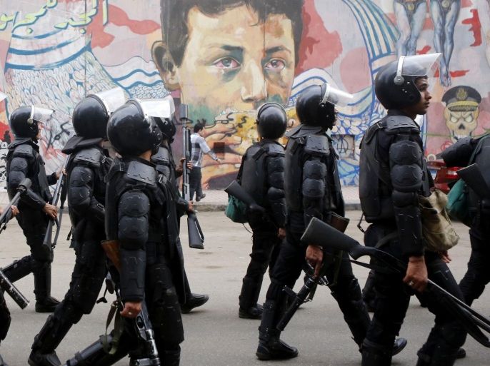 Riot police walk in front of graffiti representing anti-military power and Egypt's unrest, which reads "Glory to the unknown", along Mohamed Mahmoud Street during the third anniversary of violent and deadly clashes near Tahrir Square in Cairo November 19, 2014. Egyptian police arrested 25 individuals after four hundred protestors staged a march through downtown Cairo on the anniversary of deadly clashes with security forces three years ago, the interior ministry said on Wednesday. REUTERS/Amr Abdallah Dalsh (EGYPT - Tags: ANNIVERSARY CIVIL UNREST POLITICS)