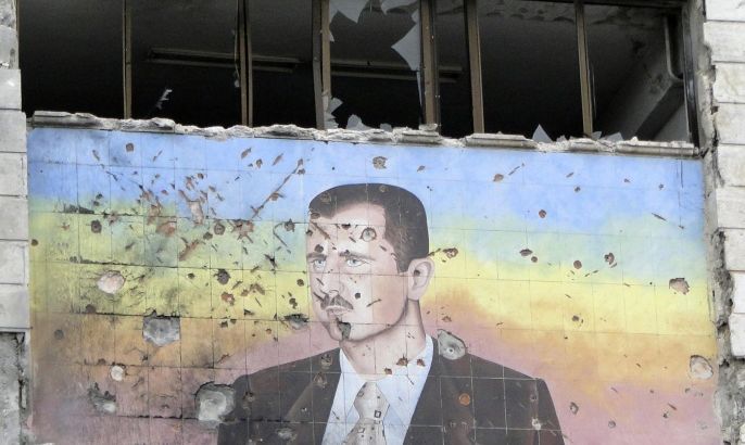 A picture of Syria's President Bashar al-Assad riddled with holes is seen on the facade of the police academy in Aleppo, after it was captured by Free Syrian Army fighters, March 4, 2013. On Sunday rebels said they captured a police academy on the outskirt of Aleppo, after days of fighting in which rebels killed 150 soldiers, while sustaining heavy casualties. REUTERS/Mahmoud Hassano (SYRIA - Tags: POLITICS CIVIL UNREST)