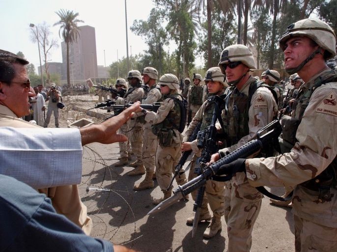 FILE - In this June 18, 2003 file photo, U.S. soldiers prevent former Iraqi soldiers from trying to enter the American headquarters during a deadly demonstration in Baghdad, Iraq. After the 2003 collapse of the Saddam Hussein's regime, hundreds of Iraqi army officers, infuriated by the U.S. decision to disband the Iraqi army, found their calling in the Sunni insurgency. (AP Photo/Victor R. Caivano, File)