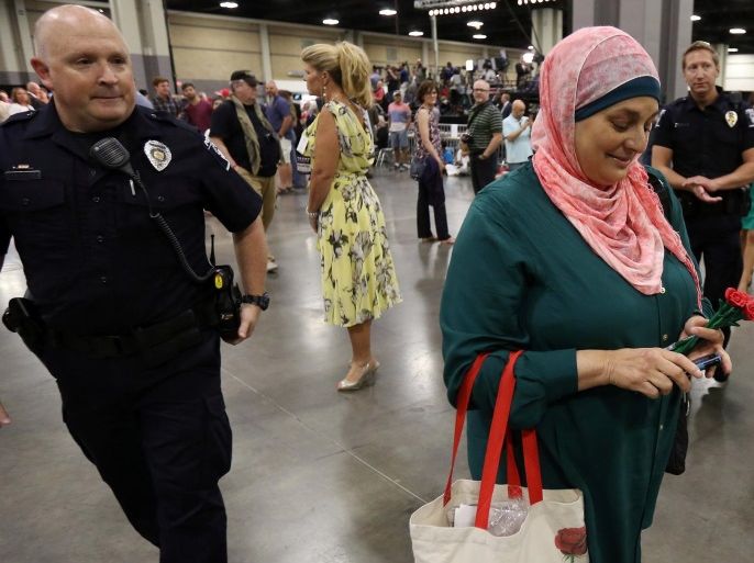 Police escort Rose Hamid, a Muslim woman from Charlotte, out of the venue before the start of Republican presidential nominee Donald Trump's campaign rally in Charlotte, North Carolina, U.S., August 18, 2016. REUTERS/Carlo Allegri