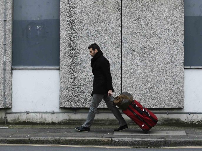 A man wheels a suitcase past a one way sign in London January 24, 2014. REUTERS/Luke MacGregor (BRITAIN - Tags: TRAVEL SOCIETY)