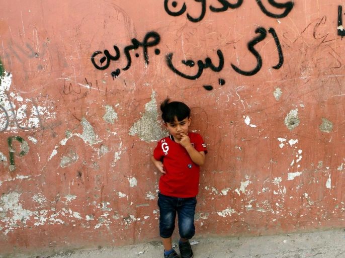 A Palestinian boy stands in front of a wall with Arabic graffiti that says 'we will return', as Palestinians mark the 68th anniversary of Nakba in Fawwar refugee camp south of the West Bank city of Hebron, 15 May 2016. 'Nakba,' or 'catastrophe, refers to the creation of the state of Israel in 1948 and the subsequent expulsion and displacement of Palestinians from their land. Palestinians keep old fashioned keys as a symbol of the homes they left behind and one day