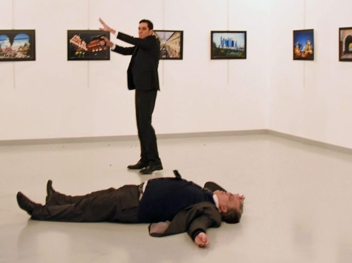 epaselect epa05683652 A gunman stands near Russian Ambassador to Turkey, Andrey Karlov's body after he shot him during an art exhibition in Ankara, Turkey, 19 December 2016. Karlov was shot by the Turkish policeman while giving a speech at the exhibition. EPA/STR TURKEY OUT