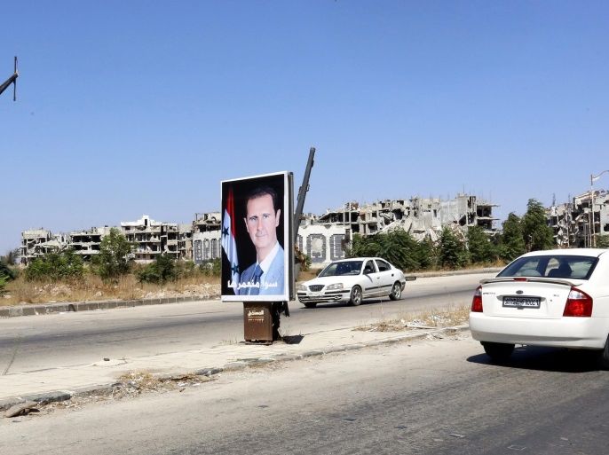 Cars drive by poster of Syrian president Bashar al-Assad that reads in arabic 'we will build it together' in the city of Homs, Syria, 19 September 2016. According to media reports, the evacuation process of some 300 gunmen from the besieged neighborhood of al-Waer in Homs that was scheduled to be carried out on the same day has been postponed to the next day. The gunmen would head to the northwestern city of Idlib in accordance with a settlement agreement that was worked out between the Syrian government and the reconciliation committees in the area a year ago. A UN-backed three-phases agreement initiated in 2015 saw the evacuation of hundreds of residents from the neighborhood, whereby detainees held in government prisons would be released and the siege imposed on the area would be lifted. Al-Waer has been the only neighborhood under rebel control in Homs after government troops consolidated their grip over the city in 2014. An estimated 75 thousand people still live in al-Waer, down from about 300 thousand before the start of the Syrian conflict in 2011.