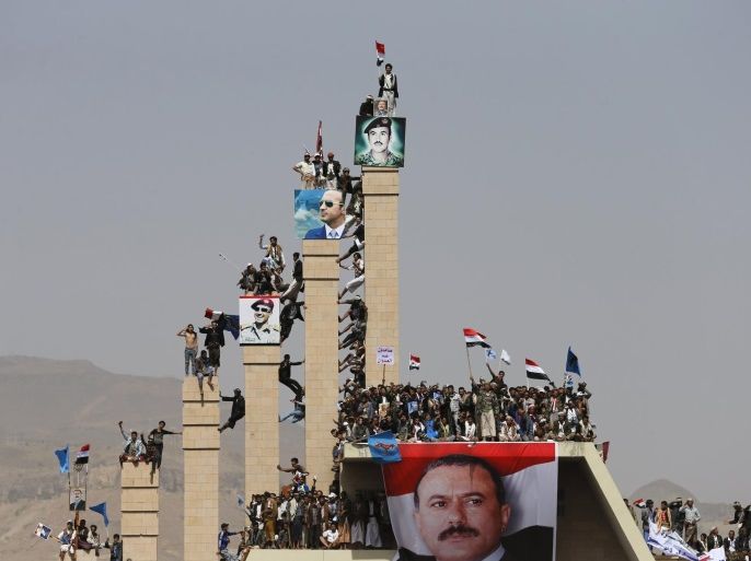 Supporters of Yemen's former President Ali Abdullah Saleh climb pillars of the Unknown Soldier Monument during a rally marking one year of Saudi-led air strikes in Yemen's capital Sanaa March 26, 2016. REUTERS/Khaled Abdullah TPX IMAGES OF THE DAY