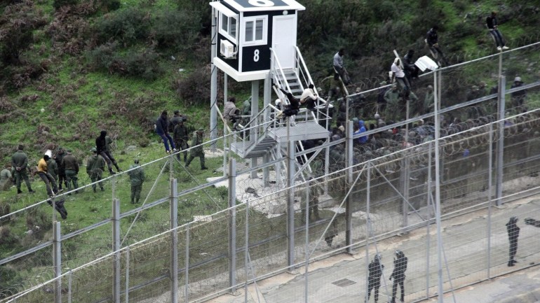 (FILE) - A file photograph showing Moroccan Police looking at immigrants trying to jump the six-meter-high fence in Ceuta, Spanish enclave on the north of Africa, 09 December 2016. Media reports on 02 January 2017 state that more than 1,100 African migrants attempted to storm a border fence in Ceuta injuring fifty Moroccans and five Spanish border guards. Only two migants made it across the border but both needed hospital treatment following their breach.