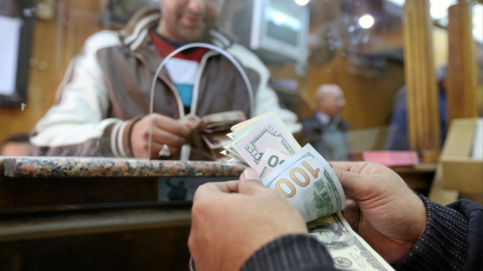 زبون يقوم باستبدال عملات الدولار بالجنيه المصري، في مصرف للعملات الأجنبية بالقاهرة