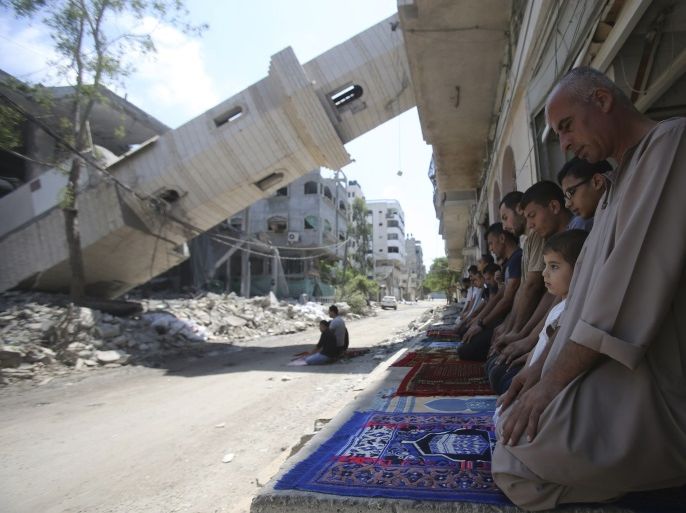 A collapsed minaret is seen as Palestinians perform Friday prayers outside the remains of a mosque, which witnesses said was hit by an Israeli air strike during a seven-week Israeli offensive in Gaza City August 29, 2014. An open-ended ceasefire, mediated by Egypt, took effect on Tuesday evening. It called for an indefinite halt to hostilities, the immediate opening of Gaza's blockaded crossings with Israel and Egypt, and a widening of the territory's fishing zone in the Mediterranean. Israel launched an offensive on July 8, with the declared aim of ending rocket fire into its territory. REUTERS/Ibraheem Abu Mustafa (GAZA - Tags: POLITICS CIVIL UNREST TPX IMAGES OF THE DAY RELIGION)