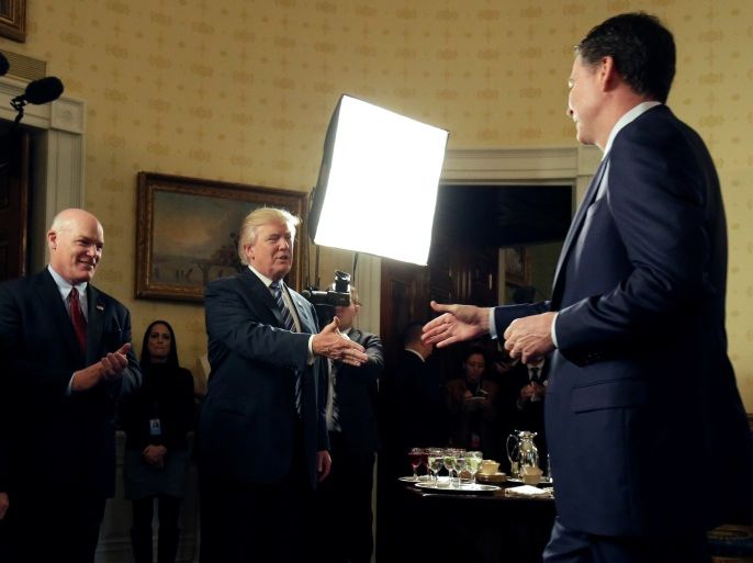 U.S. President Donald Trump greets Director of the FBI James Comey as Director of the Secret Service Joseph Clancy (L) watches during the Inaugural Law Enforcement Officers and First Responders Reception in the Blue Room of the White House in Washington, U.S., January 22, 2017. REUTERS/Joshua Roberts TPX IMAGES OF THE DAY