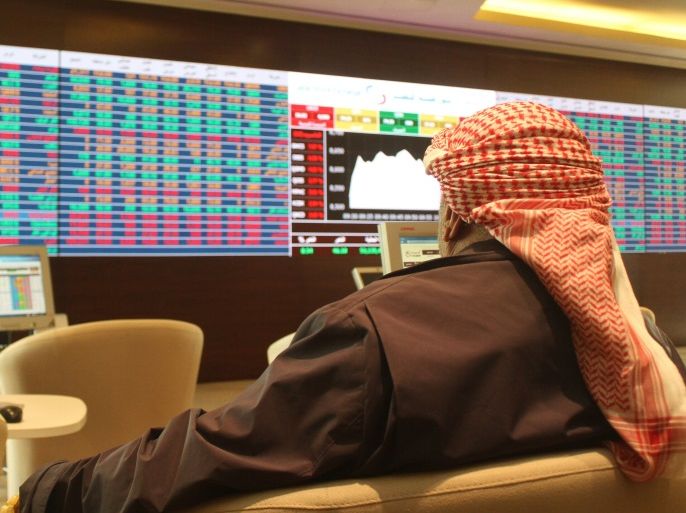 A trader looks at share prices on an electronic display at the Doha Stock Exchange, Qatar January 18, 2016. REUTERS/Naseem Zeitoon
