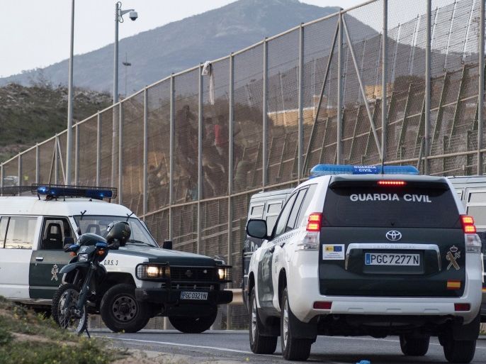 Spanish civil guards and police vans block off an area of the border between Morocco and Spain's north African enclave Melilla as a group of African migrants scaled back over the fence into the Moroccan side after a failed attempt to cross into Spanish territory March 28, 2014. Spain has more than doubled the strength of security forces at Melilla, after about 500 people stormed its fences in the biggest border rush for years earlier this month. Immigrants from all over Africa regularly dare the razor-wire fences of Spanish enclaves Ceuta and Melilla, which are surrounded by Moroccan territory and sea. The numbers have multiplied as increased naval patrols discourage attempts to get to Europe by boat. REUTERS/Jesus Blasco de Avellaneda (SPAIN - Tags: POLITICS SOCIETY IMMIGRATION)