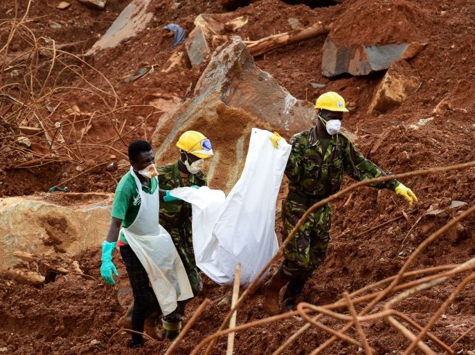 A volunteer and soldiers carry a victim across the mud, days following the partial collapse of a hillside that swept away hundreds of homes in a neighborhood of the capital Freetown on August 19, 2017.The death toll from the mudslide on August 14, 2017, and flooding that struck Sierra Leone's capital Freetown has reached 441, with around 600 others listed as missing the government said on August 19. / AFP PHOTO / SEYLLOU (Photo credit should read SEYLLOU/AFP/Getty Images)