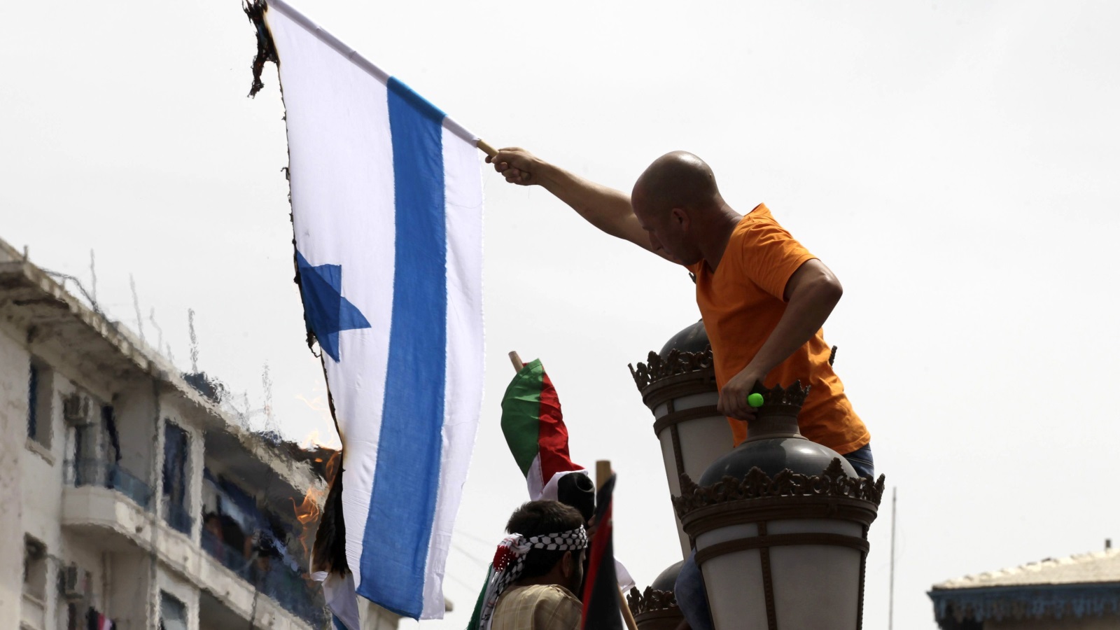  شاب جزائري يقوم بحرق العلم الإسرائيلي خلال مظاهرات للتضامن مع الفلسطينيين (رويترز)