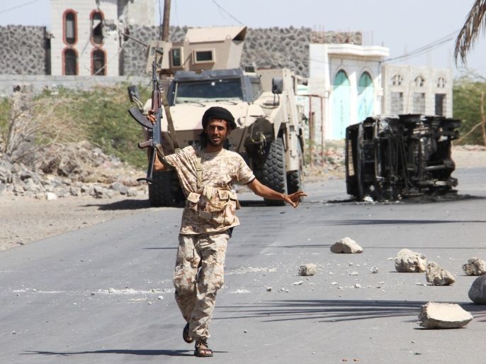 A fighter loyal to the Saudi-backed Yemeni president raises his weapon in front of the wreckage of a car in the western coastal town of Mokha as they advance in a bid to try to drive the Shiite Huthi rebels away from the Red Sea coast on February 11, 2017. / AFP / SALEH AL-OBEIDI (Photo credit should read SALEH AL-OBEIDI/AFP/Getty Images)
