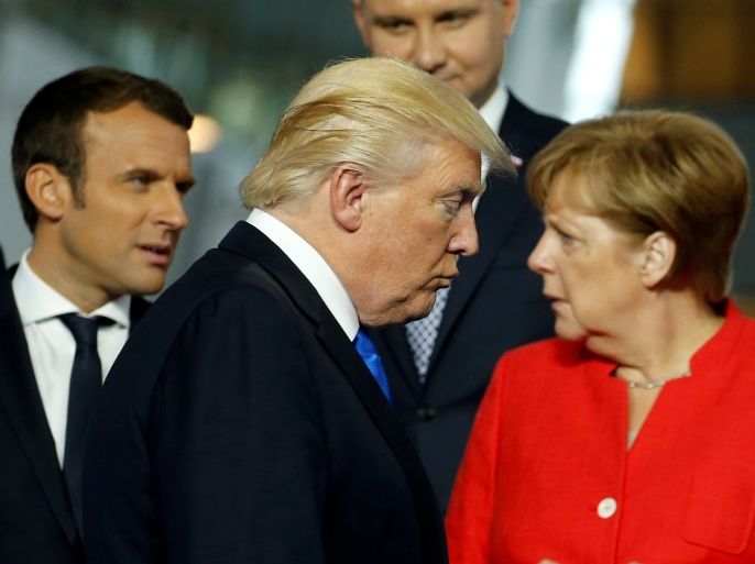 U.S. President Donald Trump (C) walks past French President Emmanuel Macron (L) and German Chancellor Angela Merkel on his way to his spot for a family photo during the NATO summit at their new headquarters in Brussels, Belgium May 25, 2017. REUTERS/Jonathan Ernst