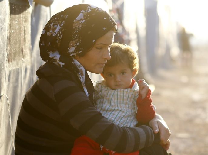 A Kurdish refugee woman from the Syrian town of Kobani holds a child in a camp in the southeastern town of Suruc, Sanliurfa province October 25, 2014. REUTERS/Kai Pfaffenbach (TURKEY - Tags: MILITARY CONFLICT POLITICS TPX IMAGES OF THE DAY)