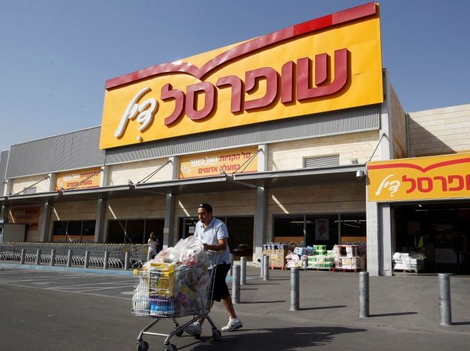 A man pushes a shopping cart outside Shufersal, Israel's largest supermarket chain, in the West Bank Jewish settlement of Mishor Adumim near Jerusalem May 5, 2013. REUTERS/Ammar Awad/Files Photo