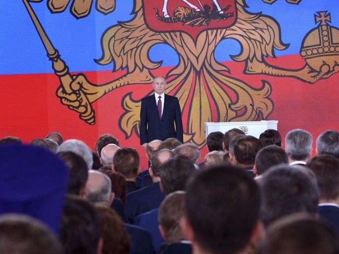 Russian President Vladimir Putin (back) stands on the stage as he addresses the Federal Assembly, including the State Duma parliamentarians, members of the Federation Council, regional governors and other high-ranking officials, in Moscow, Russia March 1, 2018. Sputnik/Alexei Nikolskyi/Kremlin via REUTERS ATTENTION EDITORS - THIS IMAGE WAS PROVIDED BY A THIRD PARTY.