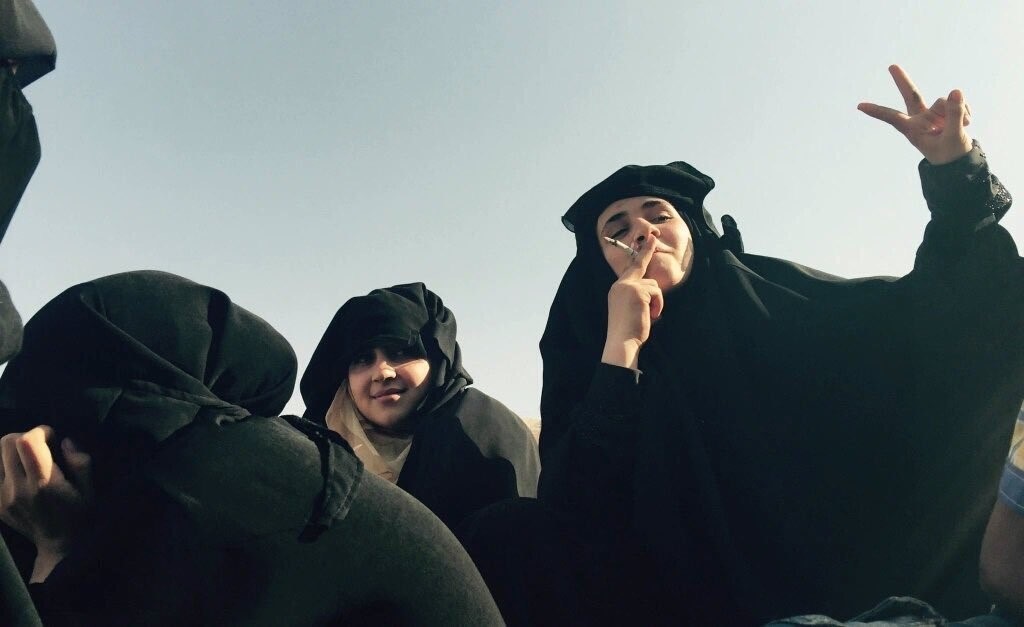 نساء منبج، وهن يدخنّ ويخلعن النقاب، رمزا لهزيمة تنظيم الدولة والتحرر من سطوته (مواقع التواصل)