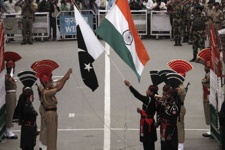 Pakistani rangers (wearing black uniforms) and Indian Border Security Force (BSF) officers lower their national flags during a daily parade at the Pakistan-India joint check-post at Wagah border, near Lahore November 3, 2014. India and Pakistan solemnly lowered their national flags at the dusk military ceremony on their main land border crossing on Monday, a day after a suicide attack killed almost 60 people on the Pakistani side. REUTERS/Mohsin Raza (PAKISTAN - Tags: POLITICS CIVIL UNREST)