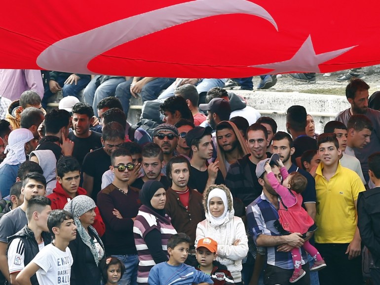 A crowd of migrants, mostly from Syria, wait at the main bus station under aTurkish flag stretched above them in Istanbul, Turkey, September 17, 2015. Hundreds of Syrians and other migrants thronged a small park in central Istanbul on Wednesday, hoping for a last chance to reach Europe before poor weather makes their favoured route from Turkey to Greece too dangerous to undertake. REUTERS/Murad Sezer