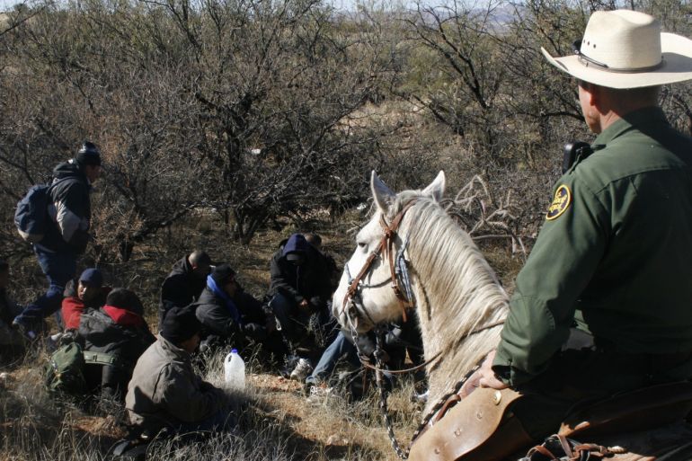 Mounted U.S. Border Patrol agent Galen Huffman watches over a group of immigrants arrested after crossing illegally from Mexico through the Altar Valley, Arizona January 9, 2008. Horses have been part of the Border Patrol since the agency was founded to secure the United States borders against liquor smugglers and unlawful immigrants in the 1920s, and now they are making a comeback. Picture taken January 9, 2008. To match feature USA-IMMIGRATION/HORSES  REUTERS/Tim Gaynor  (UNITED STATES)