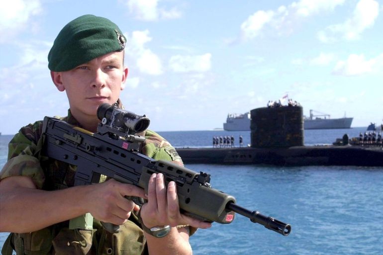 MOD02 - 20011116 - DIEGO GARCIA, BRITISH INDIAN OCEAN TERRITORY : Picture released 16 November 2001 by the British Ministry of Defence, shows a Royal Marine commando guarding a Royal Navy T class submarine arriving at the Diego Garcia US Navy base. According to newspapers reports in the UK quoting diplomatic an defence sources, the deployment of thousands of British troops in Afghanistan is deing delayed because of divisions between London and Washington over their precise role. EPA PHOTO MOD/MOD/