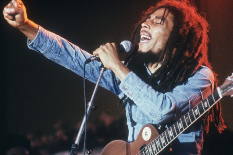 Jamaican Reggae musician, songwriter, and singer Bob Marley performs on stage, in a concert at Grona Lund, Stockholm, Sweden. He extends his fist as he sings into the microphone, with an electric guitar. (Photo by Hulton Archive/Getty Images)
