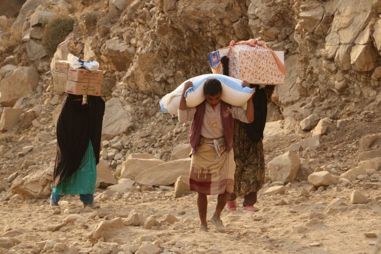 In this photo taken on Sunday, Jan. 17, 2016, Yemenis carry relief supplies as they walk along a path after Shiite rebels, known as Houthis besieging the city of Taiz, Yemen. Residents have been going hungry for weeks, the WFP said. (AP Photo/Abdulnasser Alseddik)