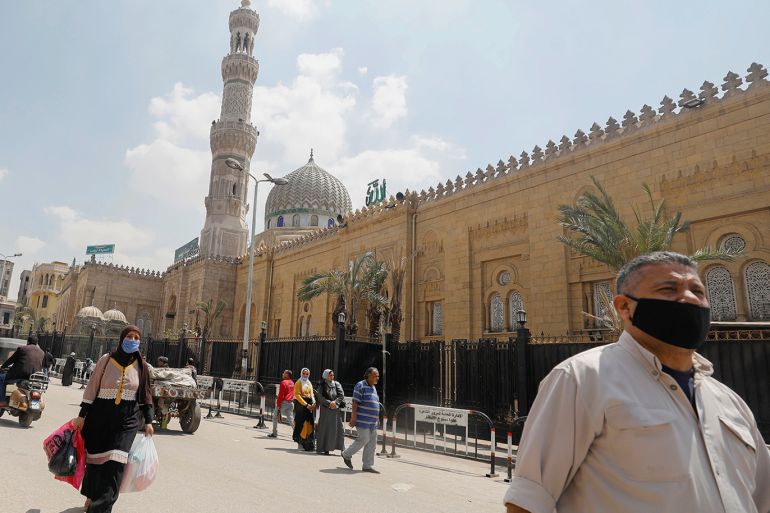 People wear protective face masks amid concerns over the coronavirus disease (COVID-19) walk in front of the closed El Sayeda Zainab Mosque near markets that sell traditional Ramadan lanterns, in Cairo, Egypt, April 12, 2020. REUTERS/Mohamed Abd El Ghany