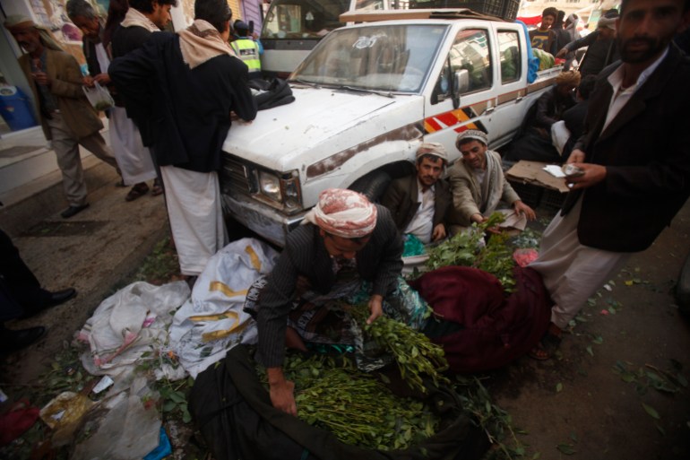 Dealers of qat, a mild stimulant, prepare qat leaves as they wait for customers outside a marketplace in Sanaa