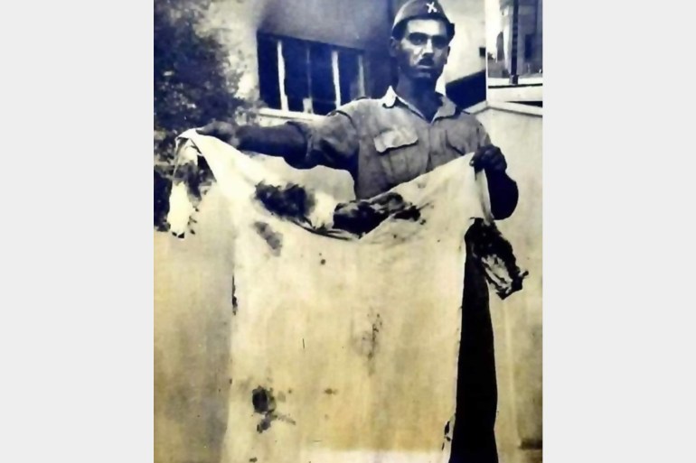 صورة لأحد الإنقلابيين يرفع ثوب ملك العراق فيصل الثاني و هو موشح بدخان الرصاص الذي اُطلق على جسده صبيحة يوم الإنقلاب 14 تموز 1958