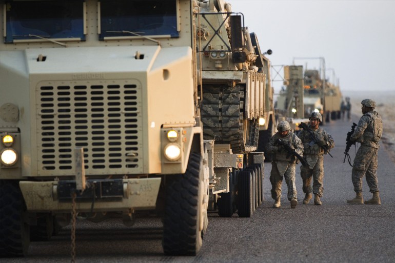 Soldiers perform a security check on their MRAP vehicles near the Kuwaiti border as part of the last U.S. military convoy to leave Iraq