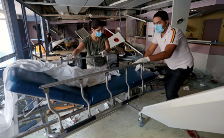 People wearing face masks move a gurney at a damaged hospital following Tuesday's blast in Beirut