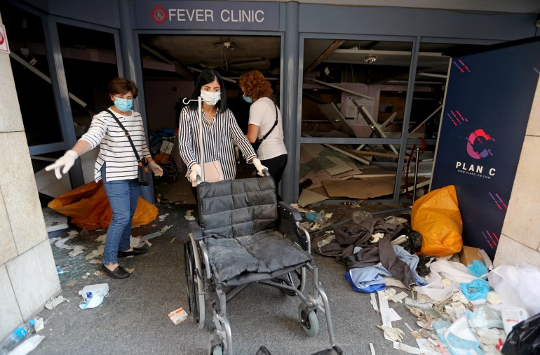 A woman pushes a wheelchair at a damaged hospital following Tuesday's blast in Beirut