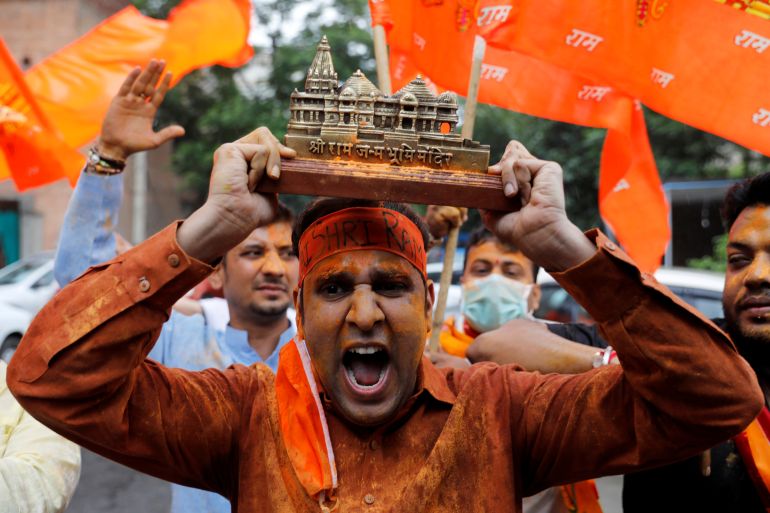 A supporter of ruling Bharatiya Janata Party (BJP) holds a model of proposed Ram Temple in Ayodhya as they celebrate the stone laying ceremony, in New Delhi