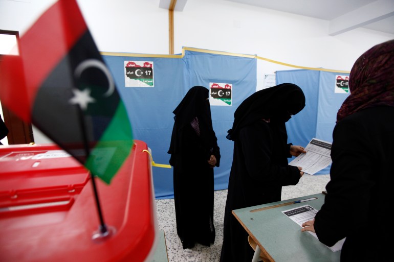 A woman looks at the ballot slip before casting her vote during the local council election in Misrata