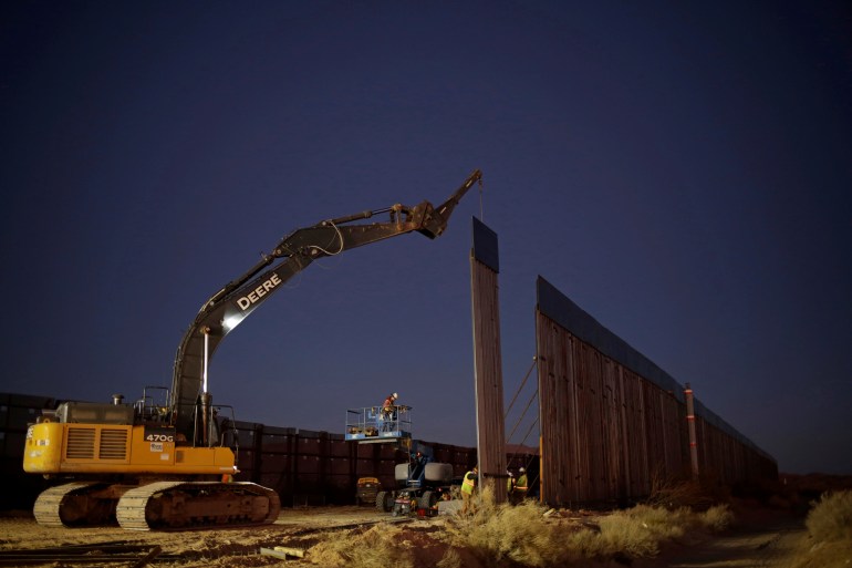 Members of a construction crew using heavy machinery work on a new section of the bollard-type border wall in Sunland Park, New Mexico, U.S., as seen from the Mexican side of the border in Ciudad Juarez