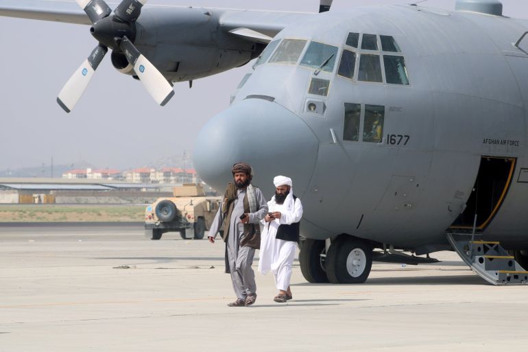 Taliban walk in front of a military airplane a day after the U.S. troops withdrawal from Hamid Karzai International Airport in Kabul