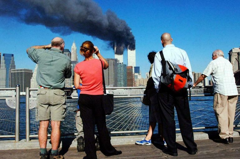 Pedestrians on the waterfront in Brooklyn, New York, look across the East River to the burning World Trade Center towers 11 September, 2001 after a terrorist attack. Picture: AFP PHOTO Henny Ray